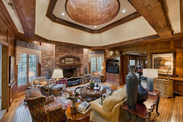 living room featuring wood walls, a tray ceiling, a healthy amount of sunlight, and light hardwood / wood-style flooring