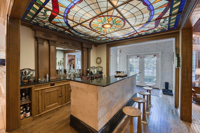 bar featuring dark stone countertops, wood-type flooring, crown molding, and french doors