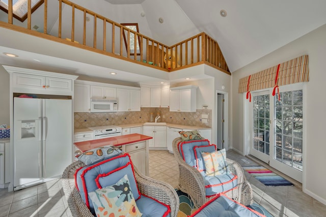 kitchen with white cabinets, high vaulted ceiling, tasteful backsplash, and white appliances