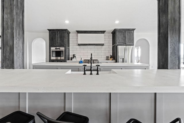 kitchen with stainless steel appliances, decorative backsplash, sink, and a kitchen breakfast bar