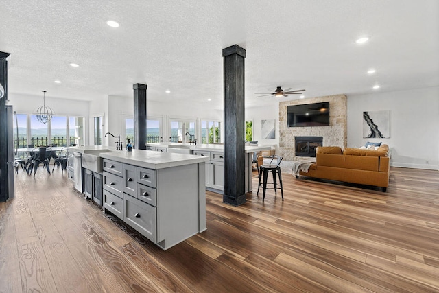 kitchen featuring a healthy amount of sunlight, a kitchen island with sink, sink, and wood-type flooring