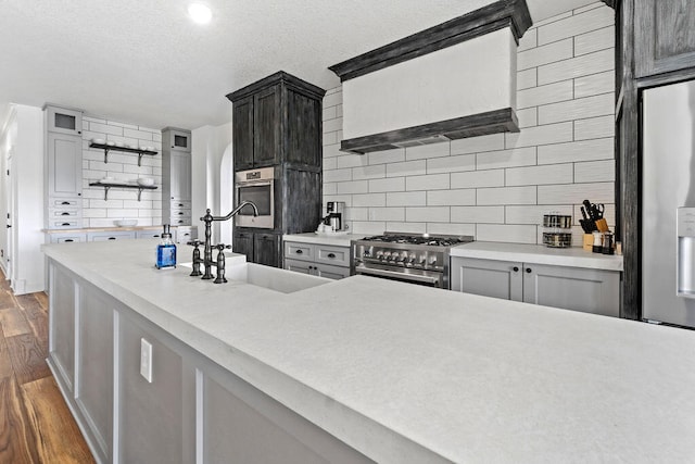 kitchen with decorative backsplash, dark hardwood / wood-style floors, range hood, sink, and appliances with stainless steel finishes