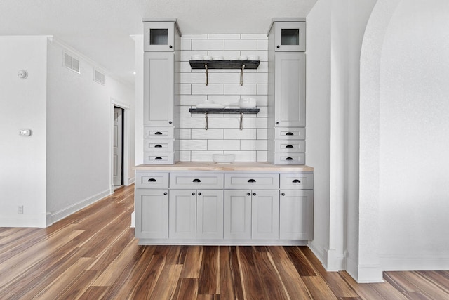 bar featuring dark hardwood / wood-style flooring, white cabinets, tasteful backsplash, and butcher block countertops