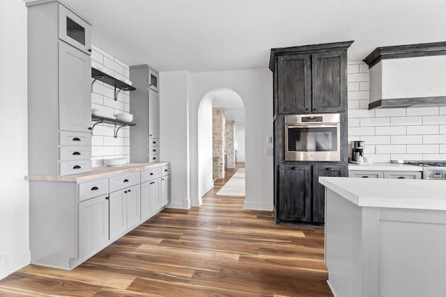 kitchen with dark brown cabinets, appliances with stainless steel finishes, dark hardwood / wood-style floors, and tasteful backsplash