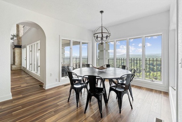 dining area with a wealth of natural light, dark wood-type flooring, and a chandelier