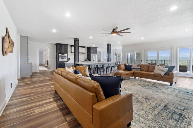 living room featuring ceiling fan, a textured ceiling, and dark hardwood / wood-style floors