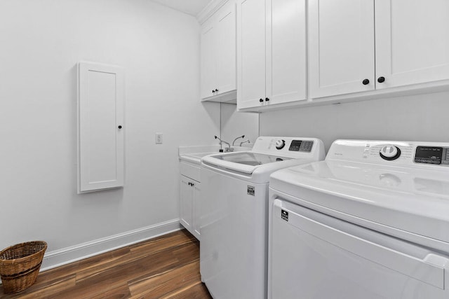 clothes washing area with sink, dark wood-type flooring, washing machine and clothes dryer, and cabinets