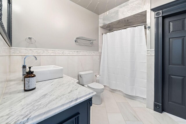 bathroom with vanity, tile walls, toilet, and walk in shower