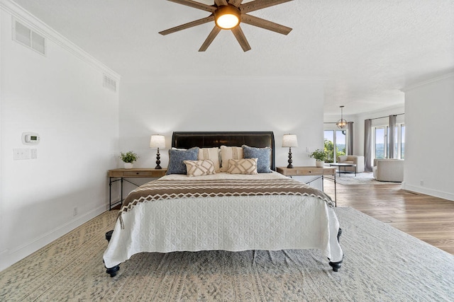 bedroom featuring crown molding, ceiling fan with notable chandelier, and light hardwood / wood-style floors