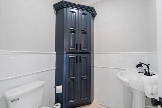 bathroom featuring tile walls, ornamental molding, and toilet