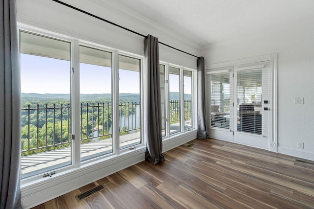 interior space featuring dark wood-type flooring, crown molding, and a water view