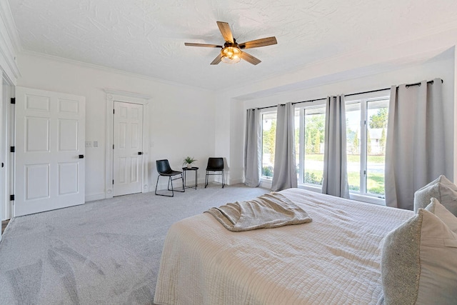 bedroom featuring ceiling fan, crown molding, a textured ceiling, and light colored carpet