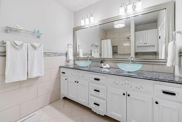 bathroom with tile walls, vanity, curtained shower, and tile patterned flooring