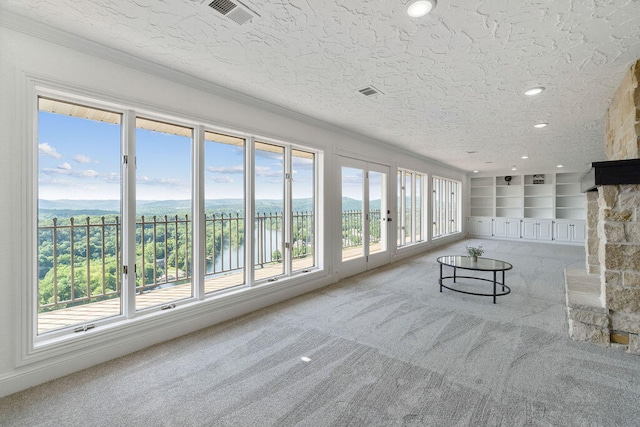 unfurnished living room featuring carpet, a textured ceiling, and plenty of natural light