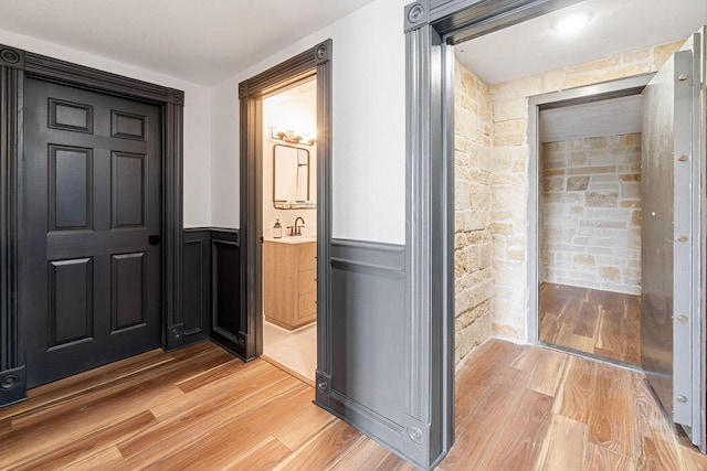 hallway with light hardwood / wood-style flooring and sink