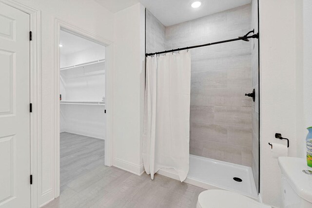 bathroom with toilet, wood-type flooring, and a shower with shower curtain