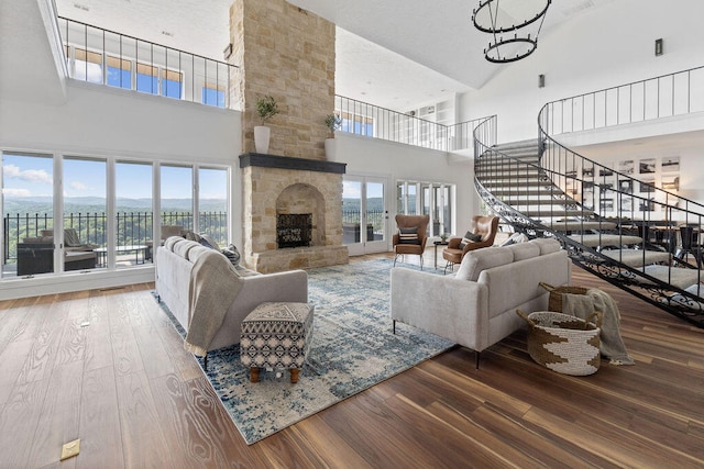 living room with hardwood / wood-style floors, a high ceiling, a fireplace, and an inviting chandelier