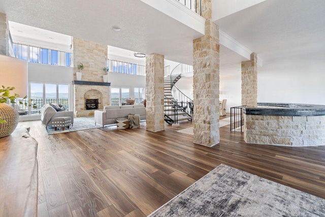 unfurnished living room featuring a towering ceiling, hardwood / wood-style flooring, a fireplace, and decorative columns