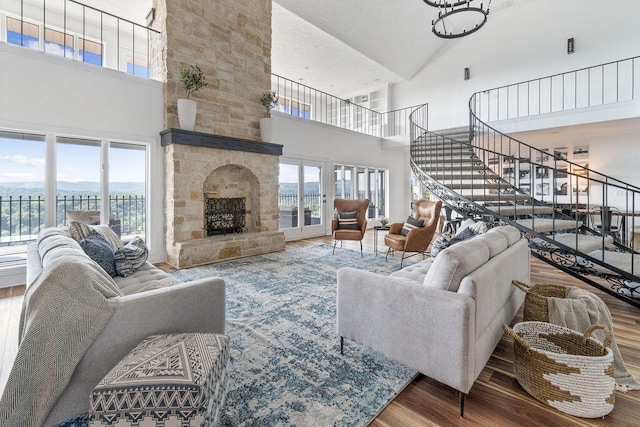 living room with a stone fireplace, hardwood / wood-style flooring, and high vaulted ceiling