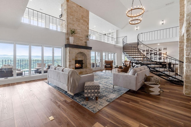 living room featuring high vaulted ceiling, wood-type flooring, a fireplace, and a wealth of natural light