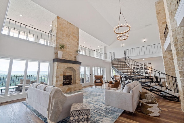 living room featuring a wealth of natural light, a stone fireplace, wood-type flooring, and high vaulted ceiling