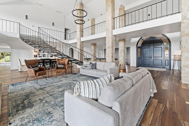 living room featuring a notable chandelier, ornate columns, high vaulted ceiling, and dark hardwood / wood-style flooring