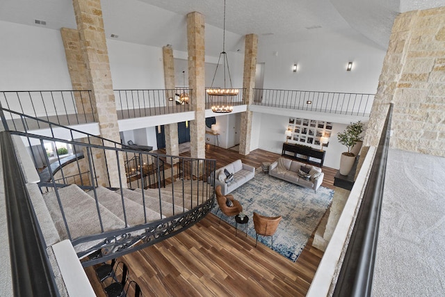 interior space with ornate columns, an inviting chandelier, wood-type flooring, and a high ceiling