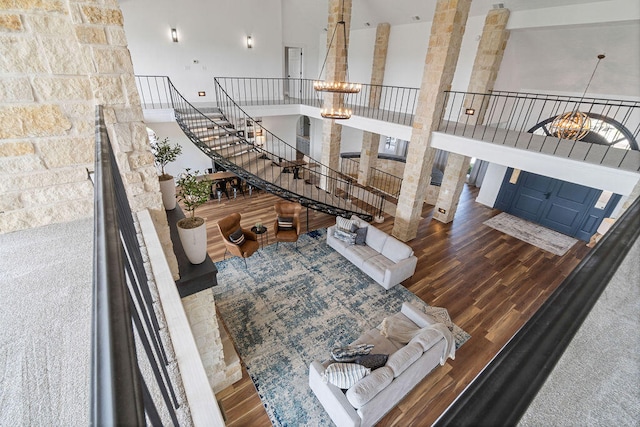 living room with an inviting chandelier, wood-type flooring, and a towering ceiling