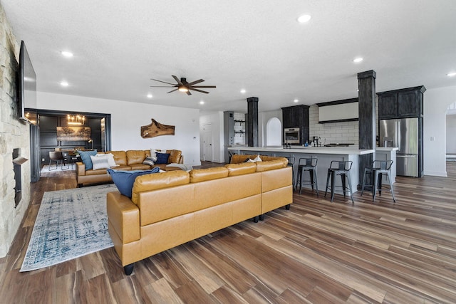 living room featuring a textured ceiling, dark hardwood / wood-style floors, and ceiling fan