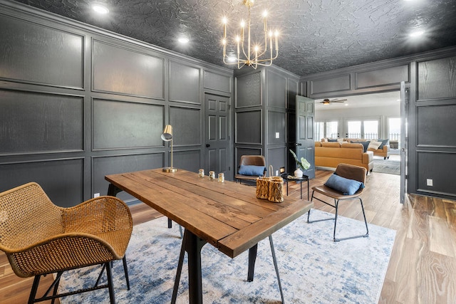 office featuring light hardwood / wood-style floors, ornamental molding, and ceiling fan with notable chandelier