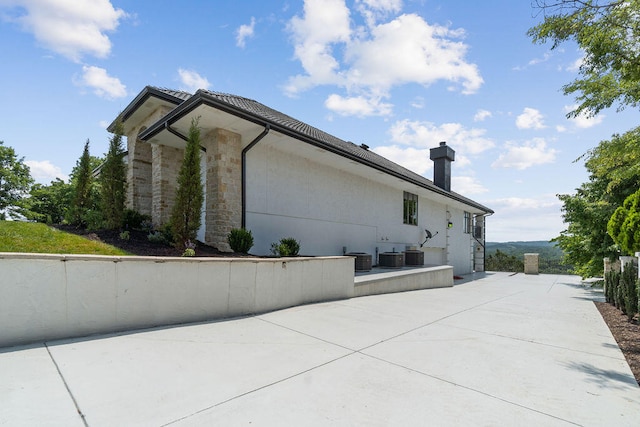 view of property exterior featuring cooling unit and a patio