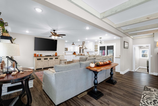 living room with beamed ceiling, dark wood-type flooring, and ceiling fan