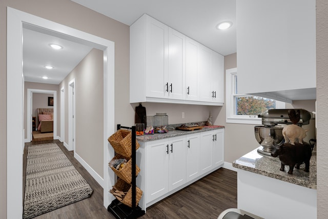 kitchen featuring white cabinets, light stone counters, and dark hardwood / wood-style flooring