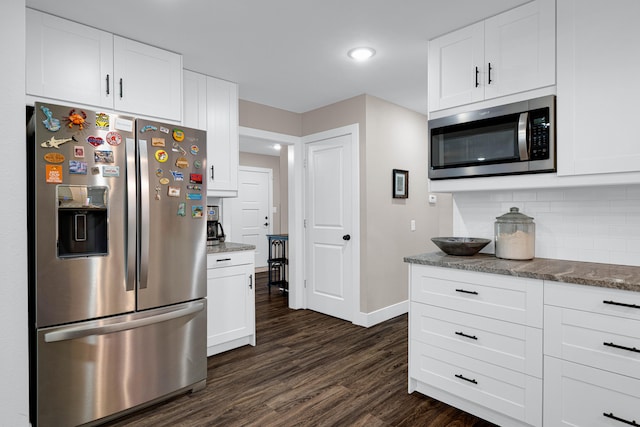 kitchen with appliances with stainless steel finishes, white cabinets, and dark wood-type flooring