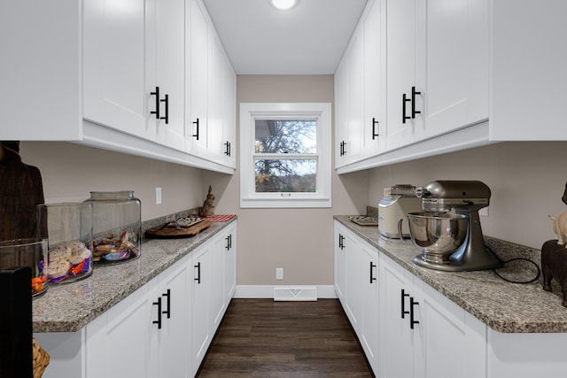 kitchen featuring white cabinets, light stone counters, and dark hardwood / wood-style flooring