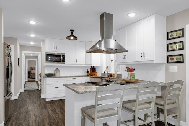 kitchen featuring wall chimney range hood, kitchen peninsula, white cabinets, and stainless steel appliances