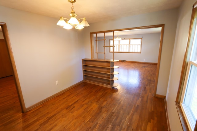 unfurnished room with an inviting chandelier and wood-type flooring