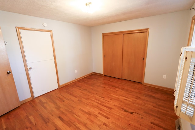 unfurnished bedroom featuring light hardwood / wood-style floors, a closet, and a textured ceiling