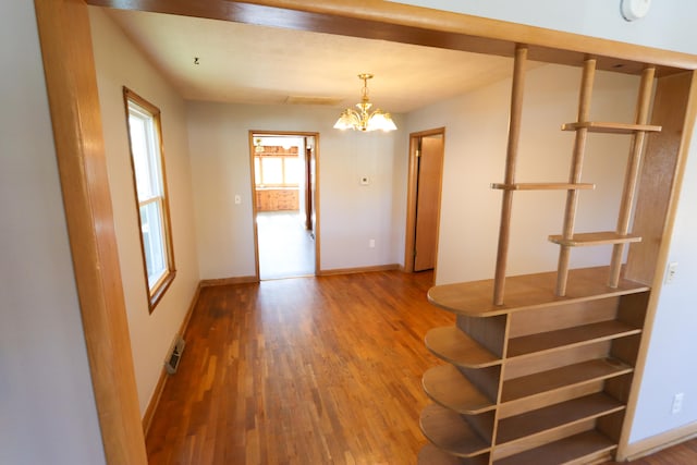 unfurnished room featuring wood-type flooring and an inviting chandelier