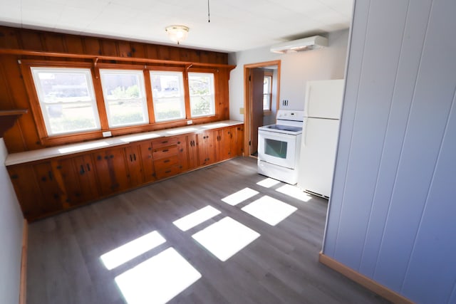 kitchen with white appliances, wooden walls, and dark hardwood / wood-style floors