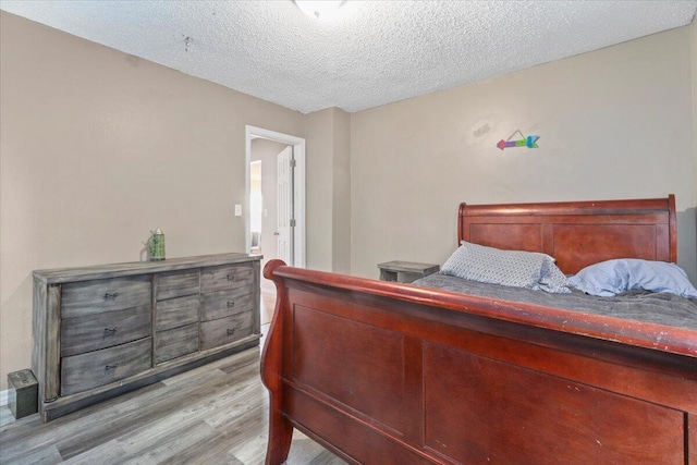 bedroom with a textured ceiling and light wood-type flooring