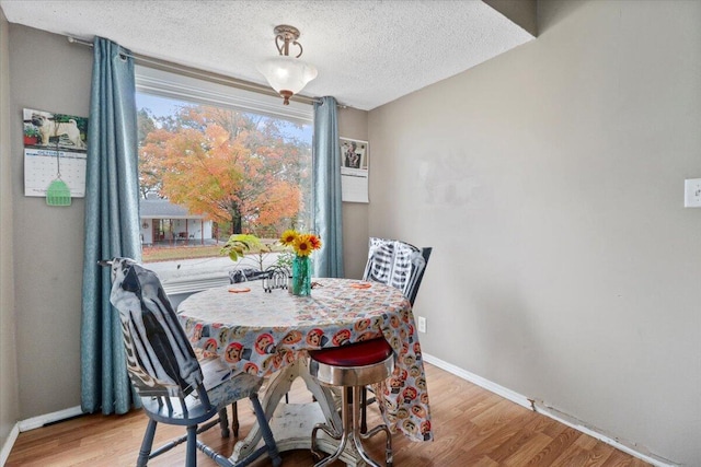 dining area with a textured ceiling and light hardwood / wood-style flooring