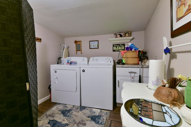 laundry room featuring dark wood-type flooring, washing machine and dryer, cabinets, and a textured ceiling