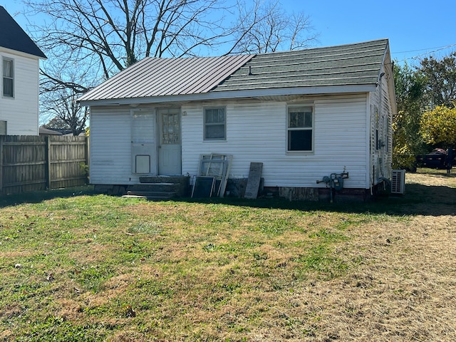 rear view of house featuring central AC unit and a yard