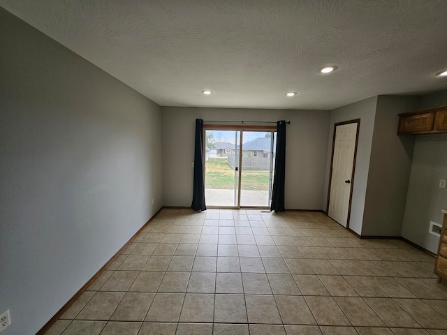 tiled empty room with a textured ceiling