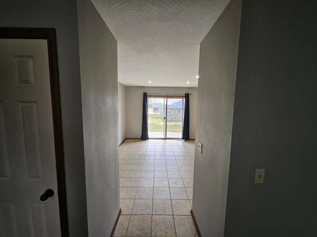 hall with a textured ceiling and light tile patterned flooring