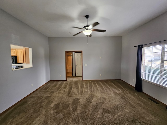 spare room featuring dark colored carpet and ceiling fan