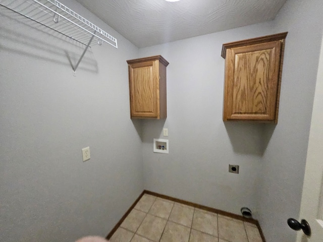 laundry area featuring electric dryer hookup, cabinets, light tile patterned floors, and hookup for a washing machine