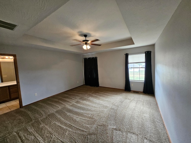 unfurnished room featuring light carpet, a textured ceiling, a raised ceiling, and ceiling fan