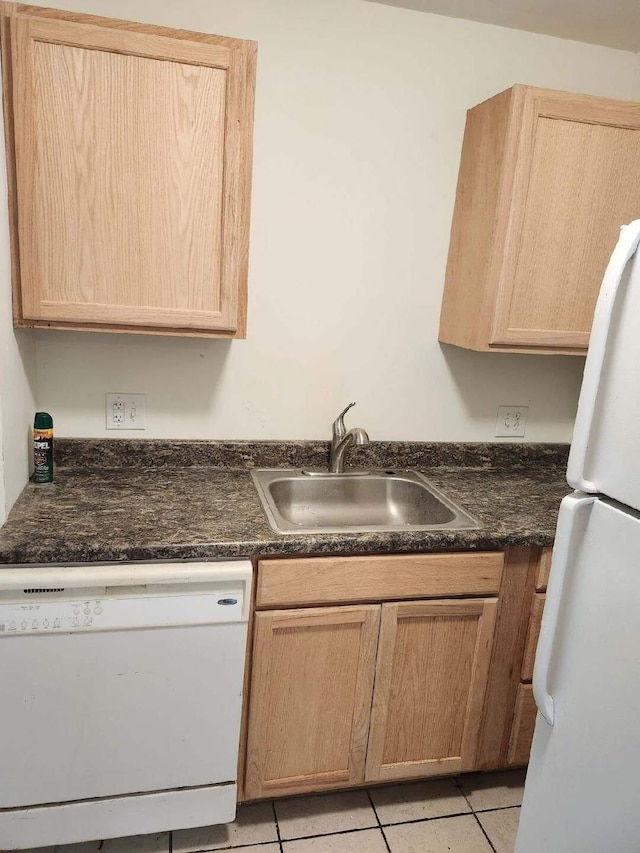 kitchen with light tile patterned flooring, white appliances, sink, and light brown cabinetry